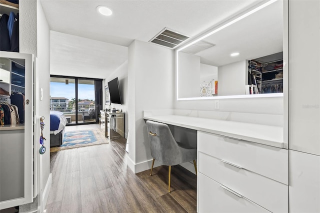 home office featuring expansive windows, dark hardwood / wood-style flooring, and built in desk