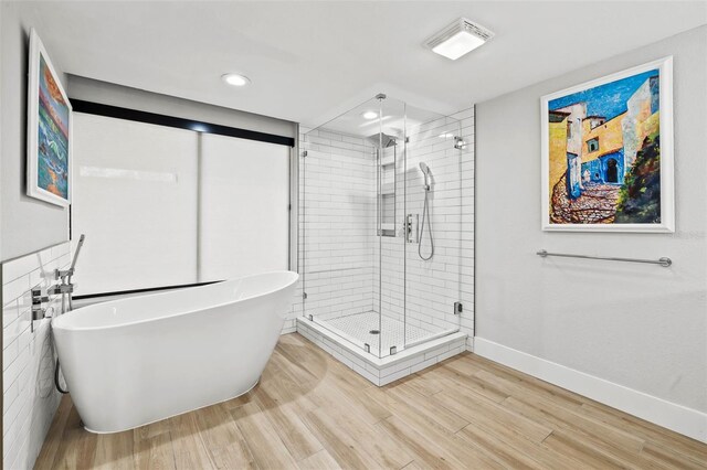 bathroom with wood-type flooring, shower with separate bathtub, and tile walls