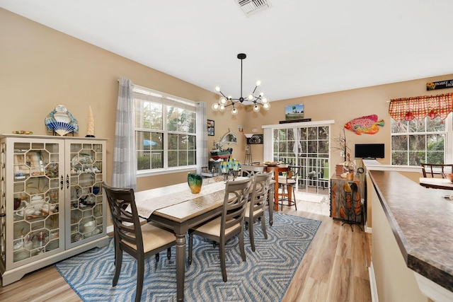 dining room with light hardwood / wood-style flooring and a notable chandelier