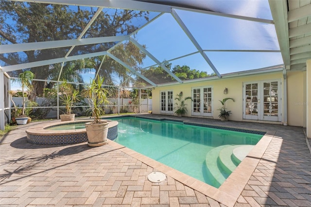 view of pool with french doors, an in ground hot tub, a patio area, and glass enclosure