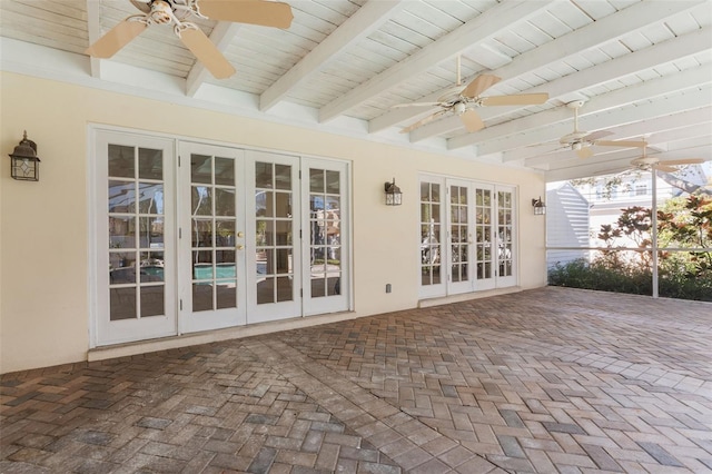 unfurnished sunroom featuring beamed ceiling, ceiling fan, and french doors