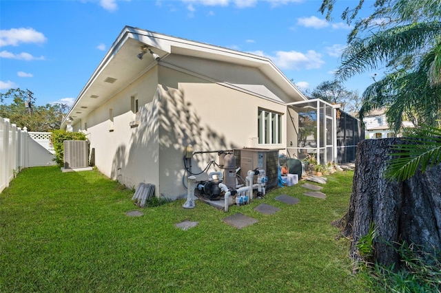 rear view of house with a yard, cooling unit, and glass enclosure