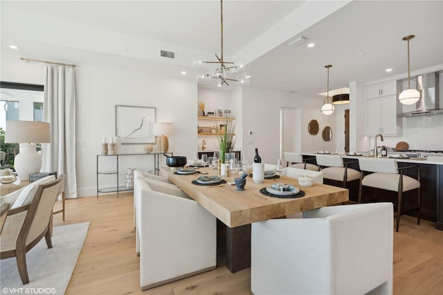 dining room with light hardwood / wood-style floors, sink, and an inviting chandelier