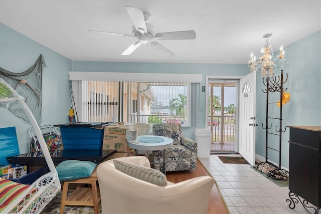 living room with ceiling fan with notable chandelier and light tile patterned floors