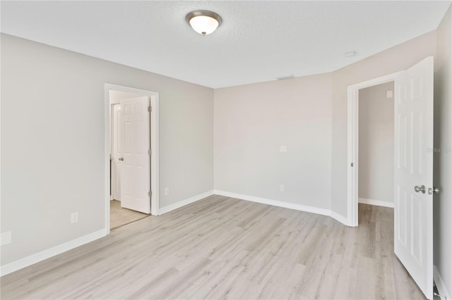 unfurnished room with light hardwood / wood-style flooring and a textured ceiling