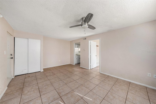 unfurnished bedroom with a textured ceiling, a closet, ceiling fan, and light tile patterned flooring