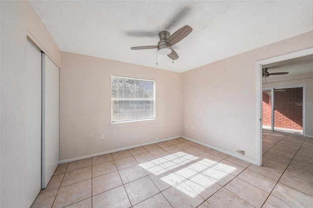 unfurnished bedroom with ceiling fan, light tile patterned floors, a textured ceiling, and a closet