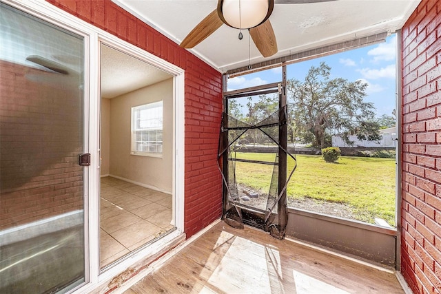 unfurnished sunroom with ceiling fan