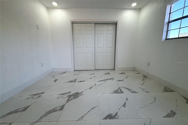 12663 Eddington Rd, Spring Hill, FL 34609 - unfurnished bedroom with baseboards, recessed lighting, light marble finish floors, and a closet