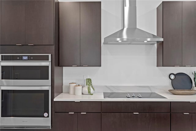 kitchen featuring double oven, dark brown cabinetry, and wall chimney exhaust hood