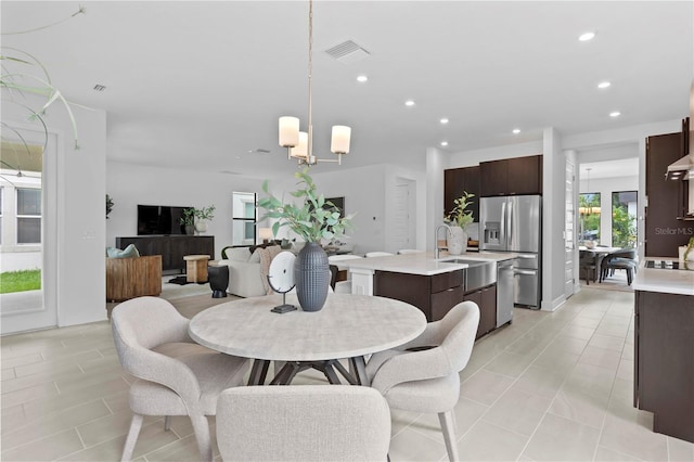 dining space featuring light tile patterned flooring, a wealth of natural light, a notable chandelier, and sink