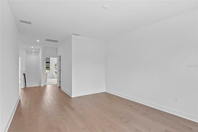 spare room featuring light wood-style floors, baseboards, visible vents, and recessed lighting