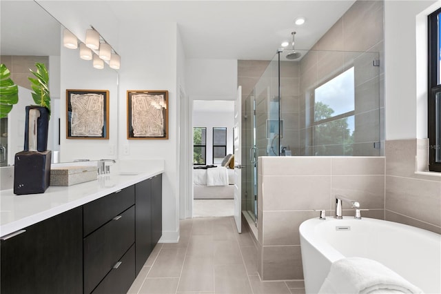 bathroom featuring plus walk in shower, vanity, tile patterned floors, and tile walls