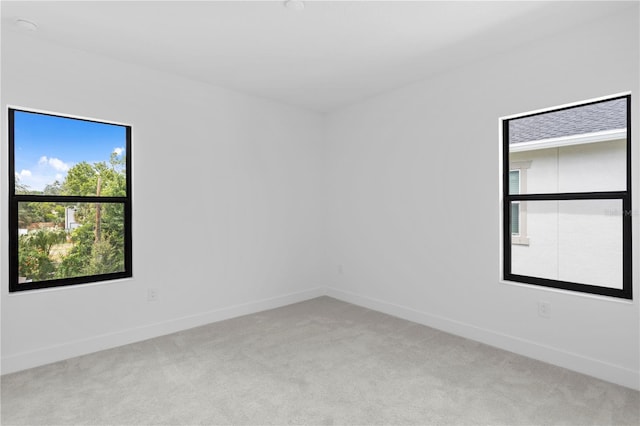 spare room featuring baseboards and light colored carpet