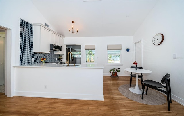 kitchen with hardwood / wood-style floors, white cabinets, lofted ceiling, sink, and backsplash