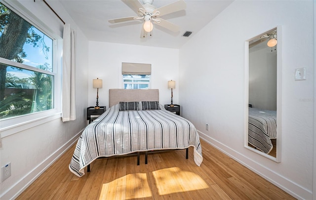 bedroom featuring multiple windows, hardwood / wood-style flooring, and ceiling fan