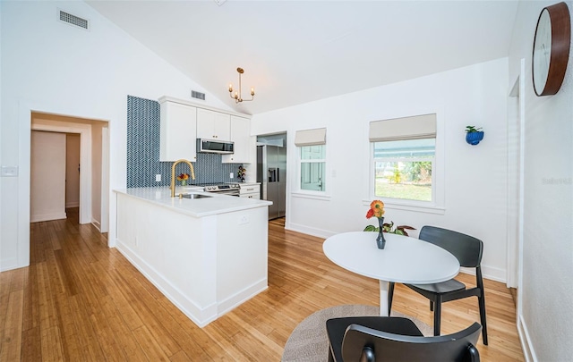 kitchen featuring kitchen peninsula, vaulted ceiling, sink, white cabinets, and stainless steel appliances