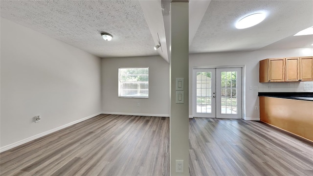 interior space featuring a textured ceiling, plenty of natural light, light hardwood / wood-style floors, and french doors