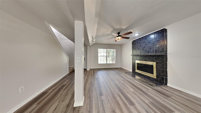 unfurnished living room featuring hardwood / wood-style flooring, a textured ceiling, and a tiled fireplace