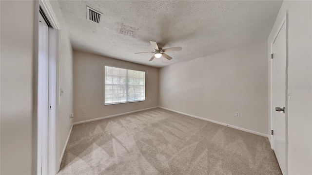 unfurnished bedroom featuring ceiling fan, light colored carpet, and a textured ceiling