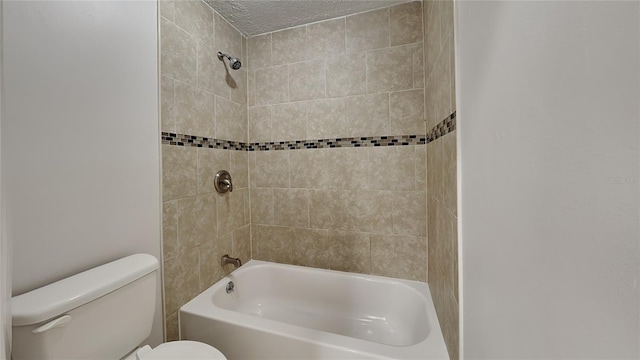 bathroom featuring tiled shower / bath combo, toilet, and a textured ceiling