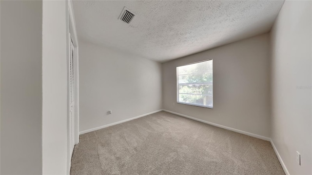 carpeted spare room featuring a textured ceiling