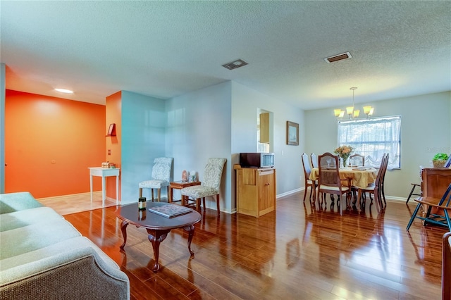 living room with hardwood / wood-style floors, a textured ceiling, and a notable chandelier