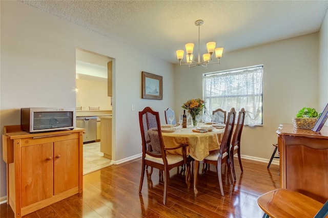 dining room with a notable chandelier, a textured ceiling, and light hardwood / wood-style flooring