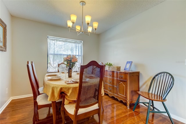 dining space with a notable chandelier, wood-type flooring, and a textured ceiling