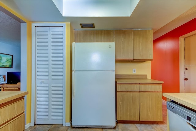 kitchen with dishwashing machine, light tile patterned floors, and white refrigerator