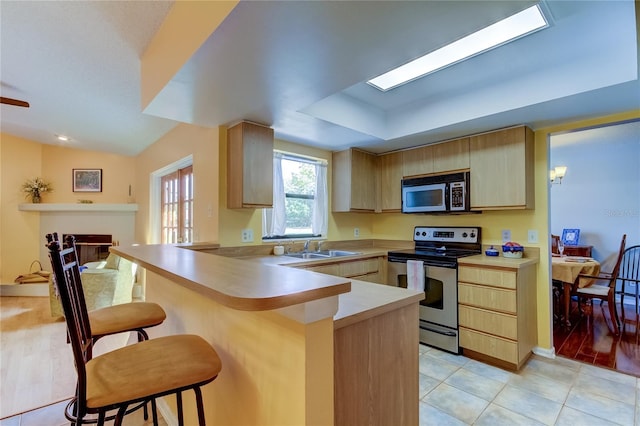 kitchen featuring a kitchen bar, kitchen peninsula, light hardwood / wood-style flooring, and stainless steel appliances