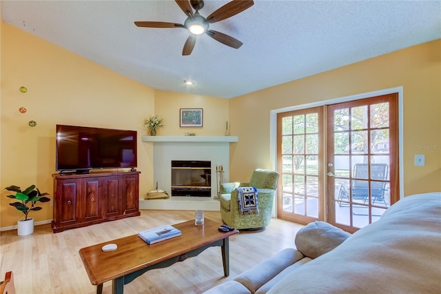 living room featuring a textured ceiling, vaulted ceiling, light hardwood / wood-style flooring, and ceiling fan