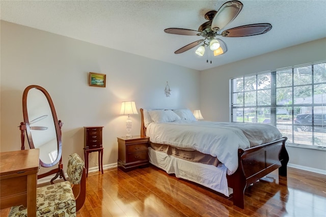 bedroom featuring wood-type flooring, a textured ceiling, multiple windows, and ceiling fan