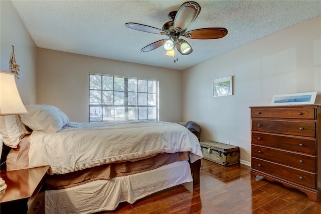 bedroom with ceiling fan, dark hardwood / wood-style flooring, and a textured ceiling