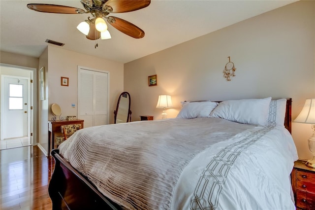 bedroom with dark hardwood / wood-style flooring, ceiling fan, and a closet