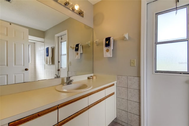 bathroom with vanity, plenty of natural light, and tile walls