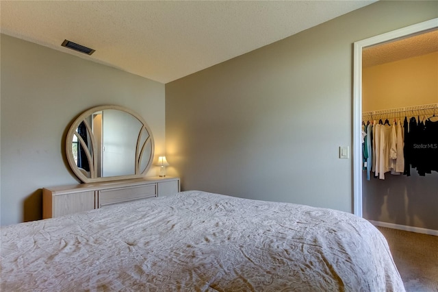 bedroom with carpet flooring, a textured ceiling, a walk in closet, and a closet