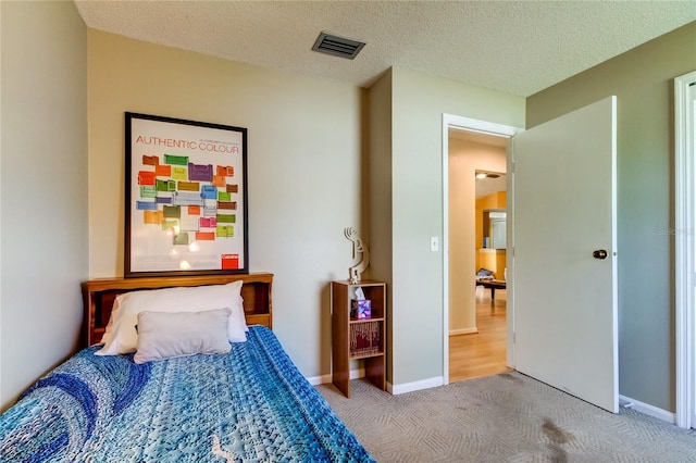 bedroom featuring light carpet and a textured ceiling