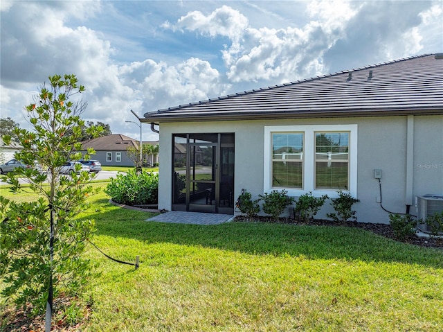 back of house with central AC, a sunroom, and a yard