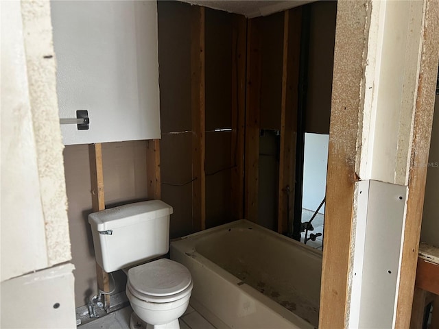 bathroom with a bathing tub, water heater, and toilet