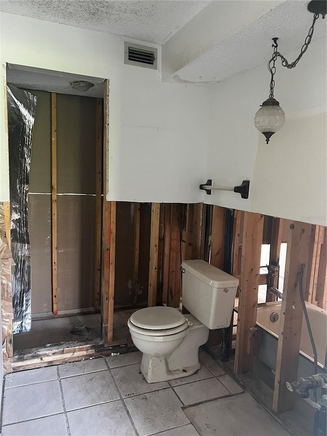 bathroom featuring wood walls, a textured ceiling, and toilet