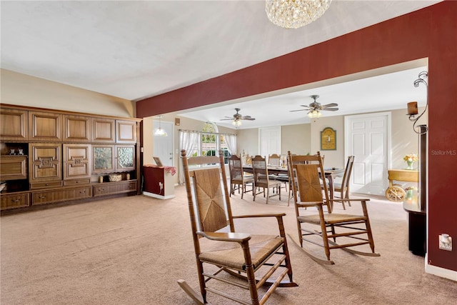 dining space with light carpet and ceiling fan with notable chandelier