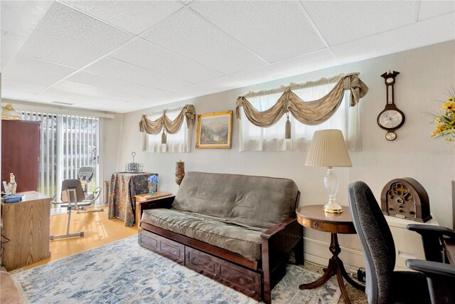 living room featuring a drop ceiling and hardwood / wood-style flooring