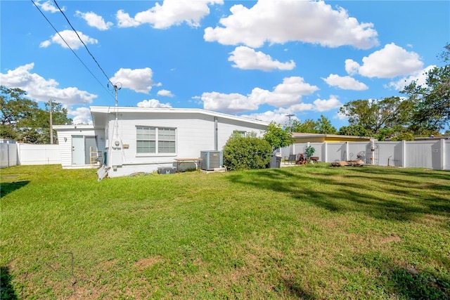 rear view of property with a lawn and central AC