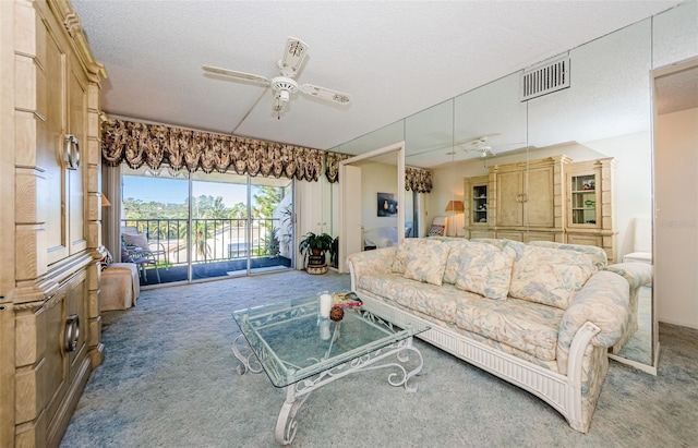 living room with carpet, ceiling fan, and a textured ceiling