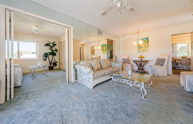 carpeted living room featuring a textured ceiling and ceiling fan with notable chandelier