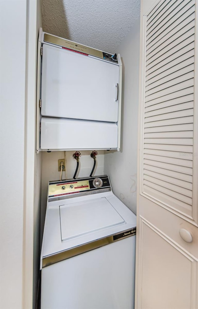 laundry room with stacked washer / drying machine and a textured ceiling