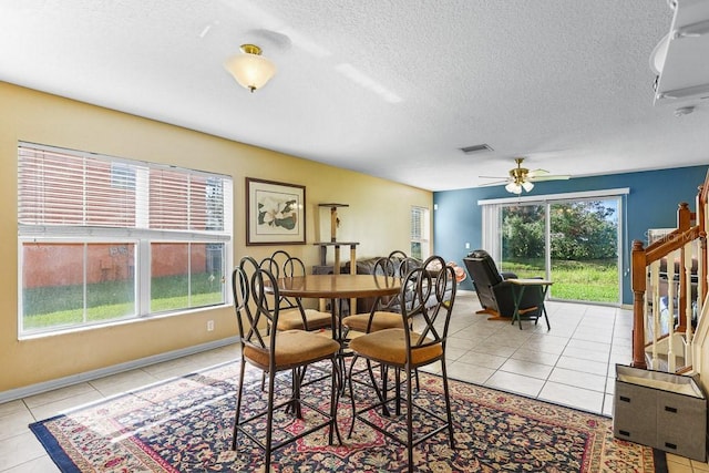 tiled dining room with ceiling fan and a textured ceiling