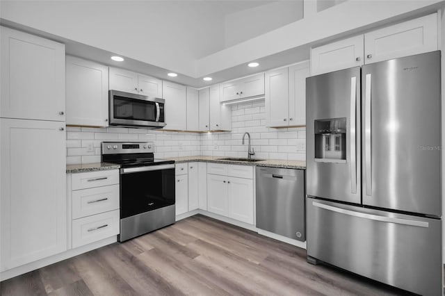 kitchen with light stone counters, white cabinetry, sink, and appliances with stainless steel finishes