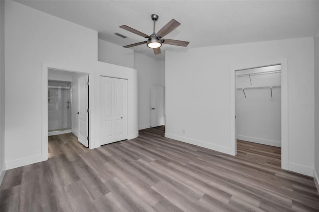 2292 Austrian Ln Unit 34, Clearwater, FL 33763 - unfurnished bedroom with wood finished floors, connected bathroom, baseboards, a ceiling fan, and a walk in closet